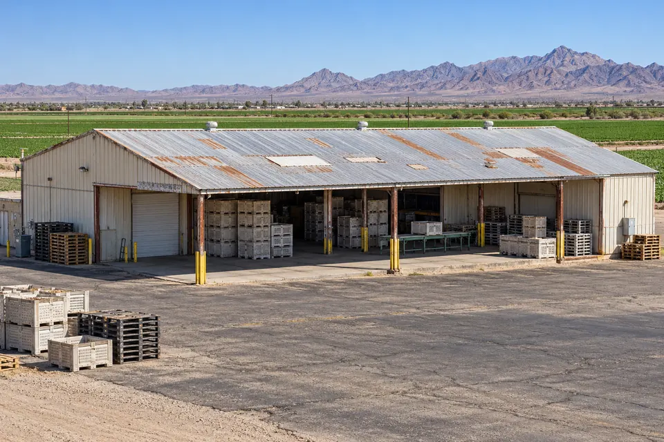 Open-sided metal packing shed with pallets on a farm lot near Yuma